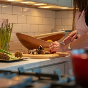 A woman in a kitchen chopping vegetables on a cutting board