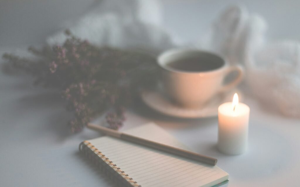 White candle on white ruled paper beside white ceramic mug