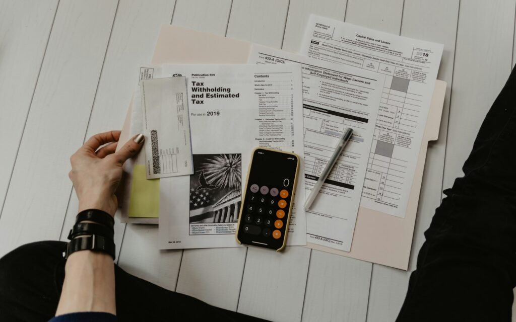 Person holding paper near pen and calculator