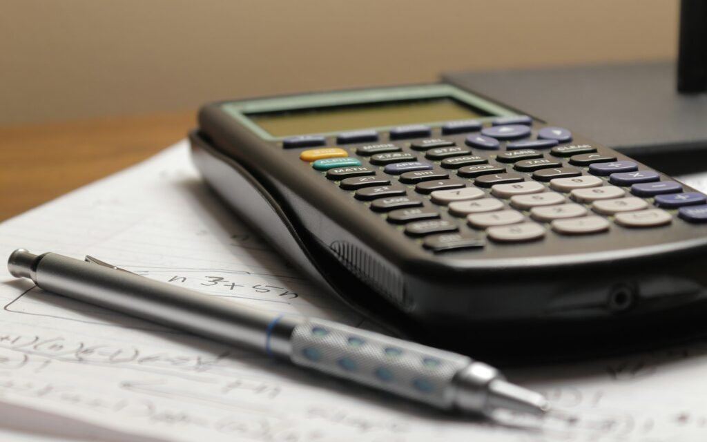 A calculator and a pen sitting on top of a piece of paper
