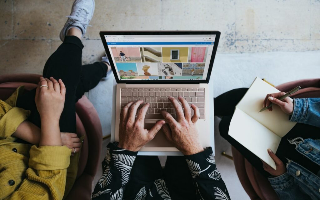 Person using microsoft surface laptop on lap with two other people
