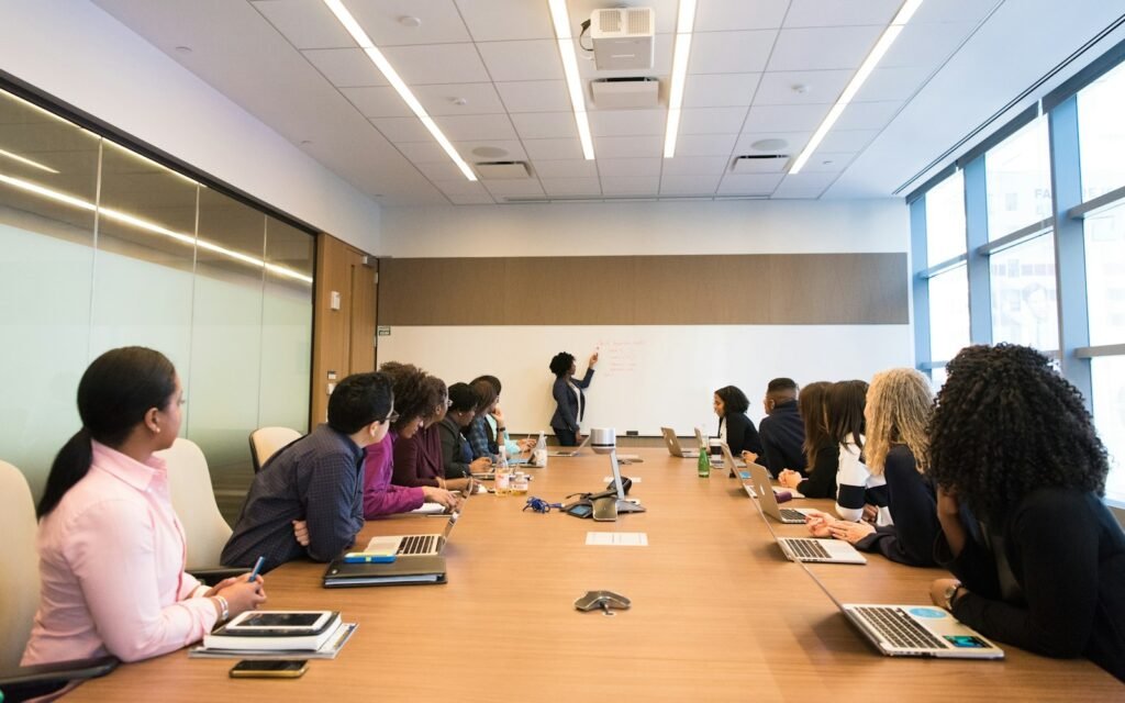 People on conference table looking at talking woman
