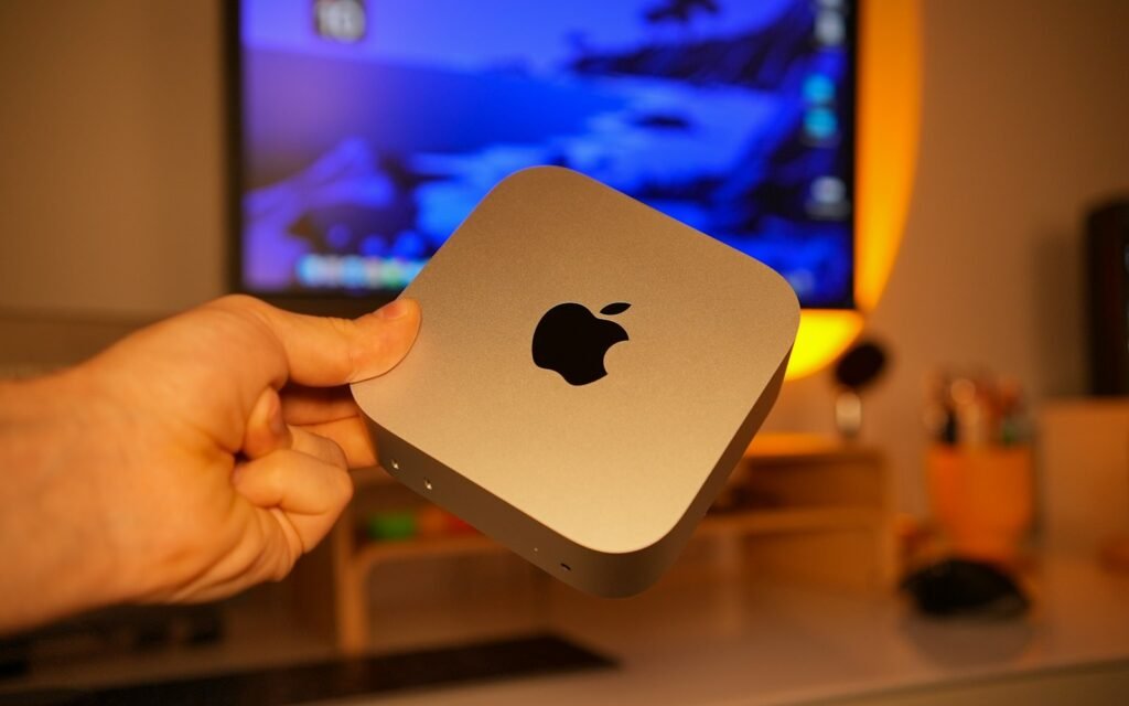 Hand holding a small silver apple computer