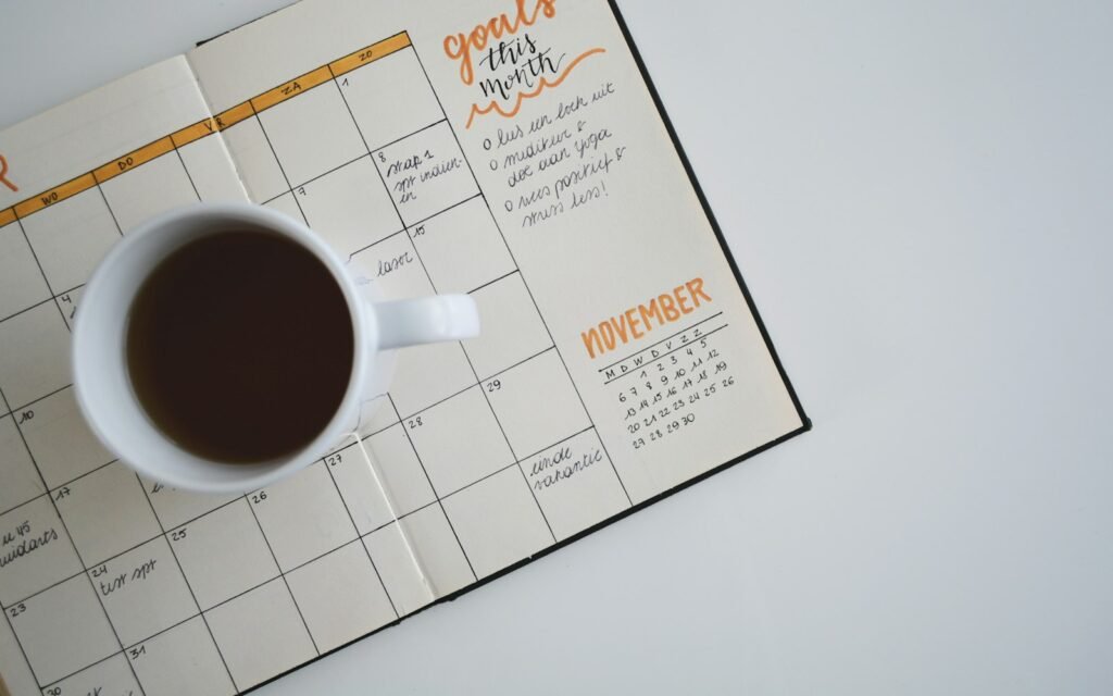 White ceramic mug with coffee on top of a planner
